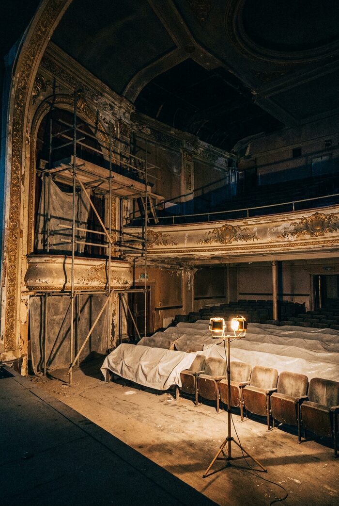 An empty 1930s cinema auditorium mid-restoration with scaffolding and dust sheets